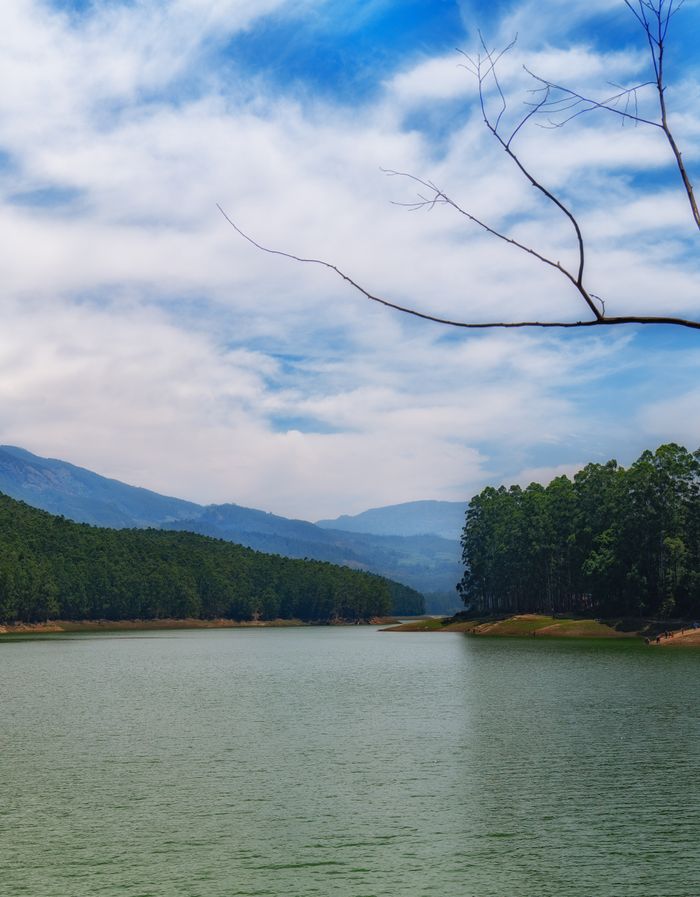 Tranquil lake surrounded by lush forests and mountains in Kerala