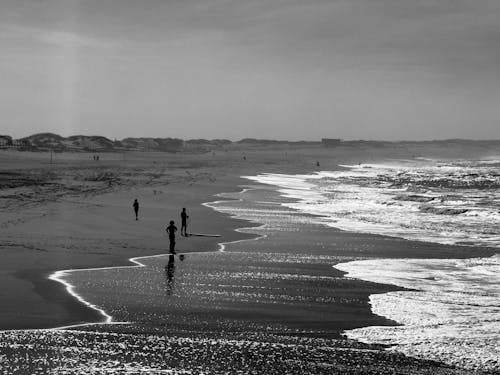 Black and white photograph of people walking on the beach