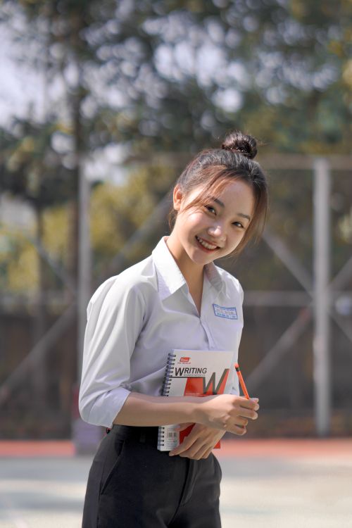 Free Teen girl smiling in uniform with a notebook outside on a sunny day. Stock Photo