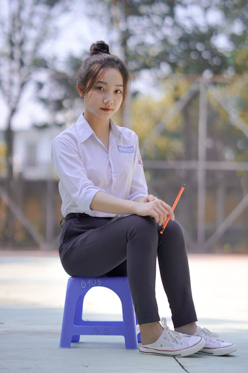 Teenager Wearing Uniform and Sitting on Little Chair 