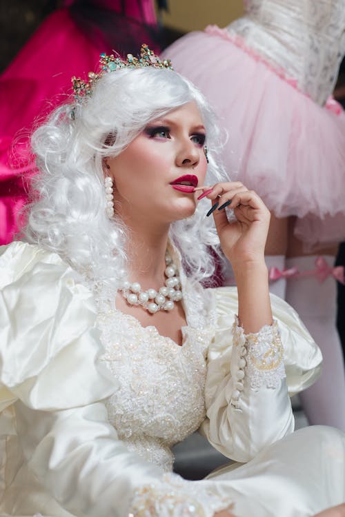 A woman in a white dress and tiara talking on a cell phone