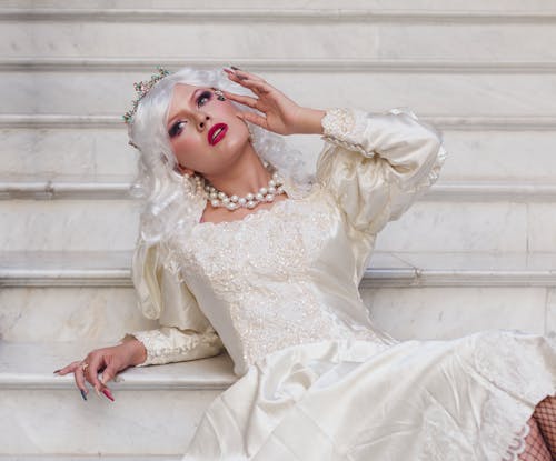 A woman in a wedding dress is laying on some stairs