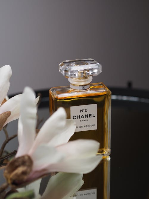 A bottle of chanel perfume sitting on a table next to a flower