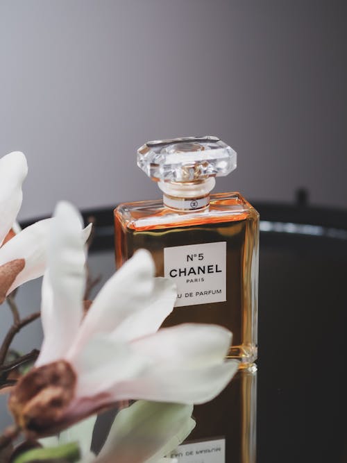 A bottle of chanel perfume sitting on a table with flowers