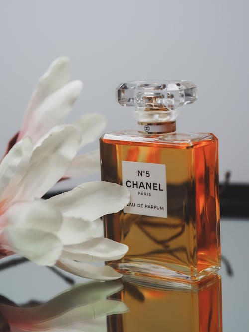 A bottle of chanel perfume sitting on a table next to a flower