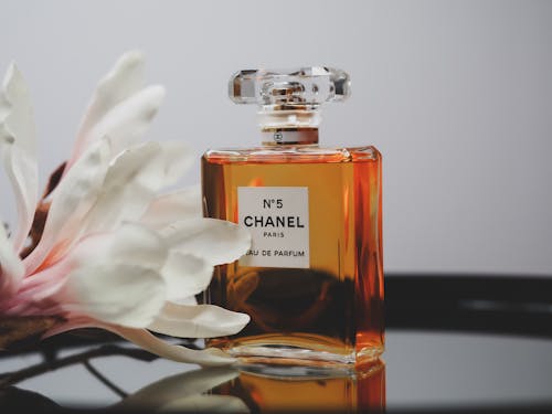 A bottle of chanel perfume sitting on a table with a flower