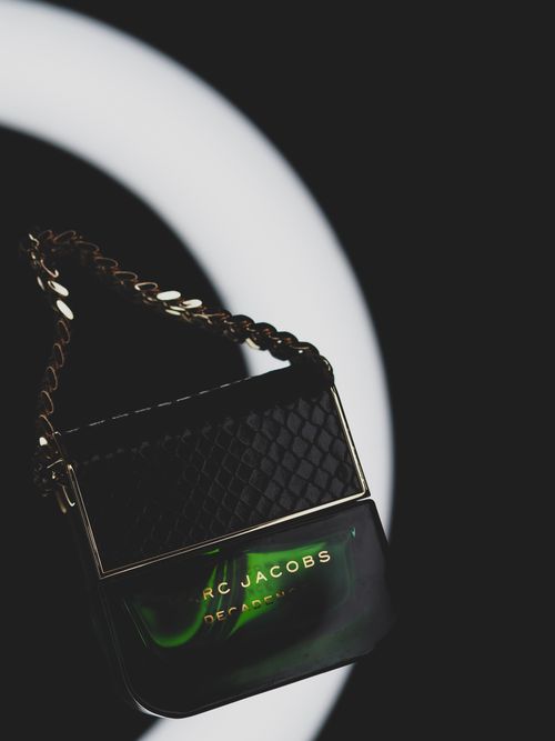 Free Elegant Marc Jacobs Decadence perfume bottle with gold chain, studio lighting. Stock Photo