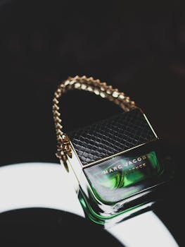 Elegant perfume bottle with chain detail on a sleek black surface, perfect for fashion and cosmetics.