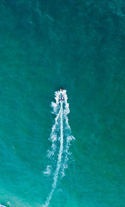 Free Aerial shot of a motorboat leaving a wake on turquoise water, perfect for travel imagery. Stock Photo