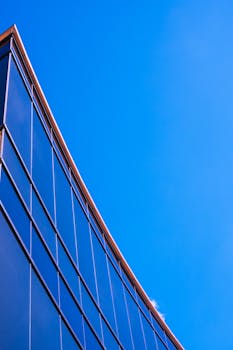 清澈的蓝天映衬下，光滑的现代玻璃建筑立面更显设计感