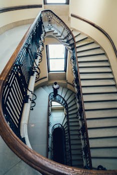 宏伟的螺旋楼梯上，一个孤独的人影正沿着复杂的铁栏杆向上攀登