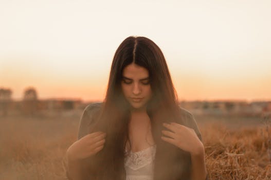 日落时分，一位年轻女子在田野里，显得平静而沉思