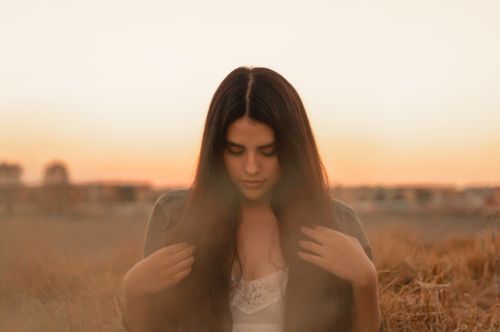 Free A young woman in a field at sunset, embodying serenity and contemplation. Stock Photo