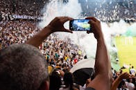 球迷们在体育场看台上用智能手机捕捉激动人心的足球比赛场景