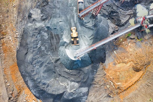 Aerial view of a large industrial mining site with heavy machinery and conveyor belts in operation.