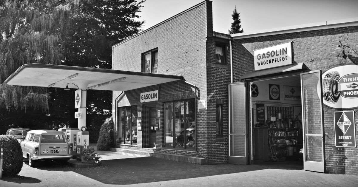 Black and white photo of a vintage gas station with a classic car.