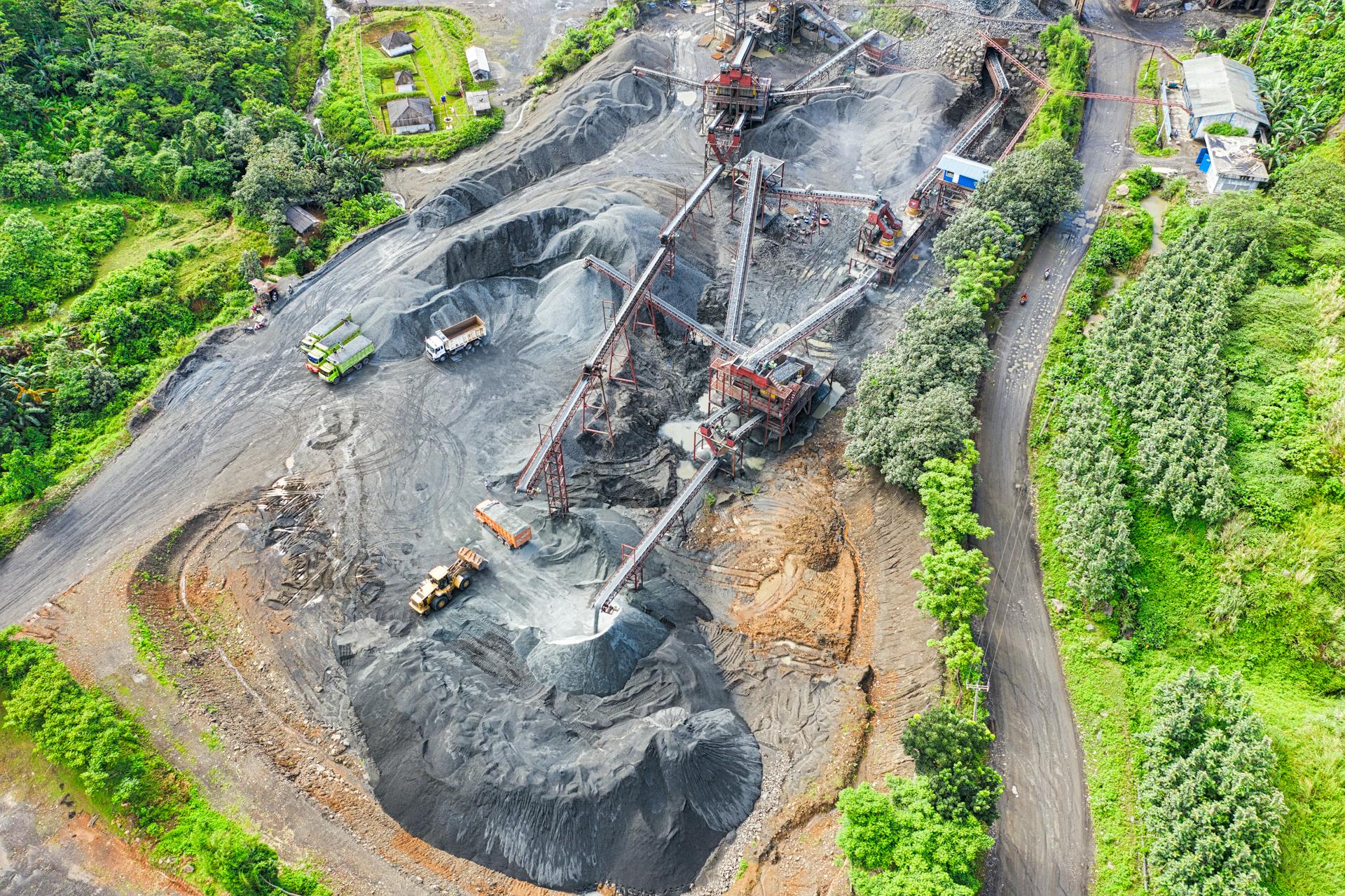 Aerial shot of a mining site surrounded by greenery, showcasing industrial activity.