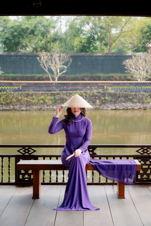 A woman in a purple dress sitting on a wooden bench