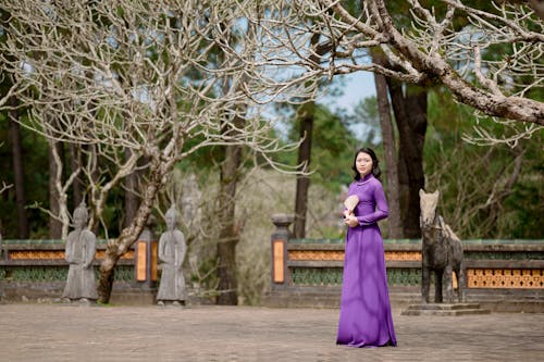 Woman in Purple Dress among Trees at Temple