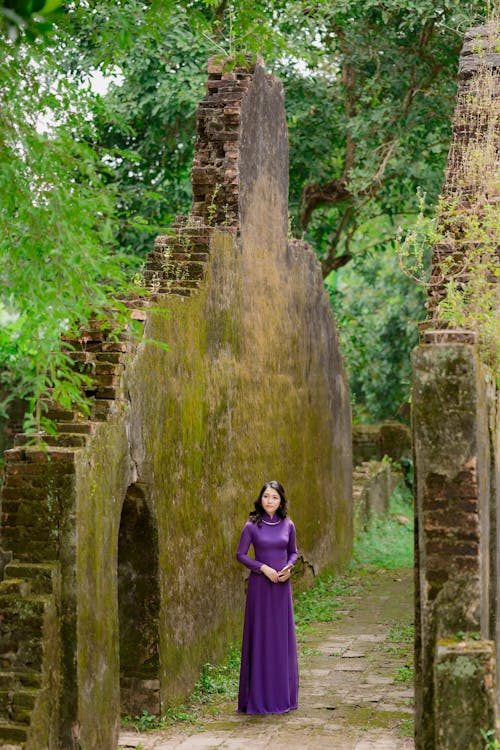 Woman in Purple Dress Standing in Ruins