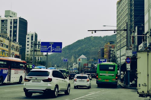 A city street with cars and buses driving down it