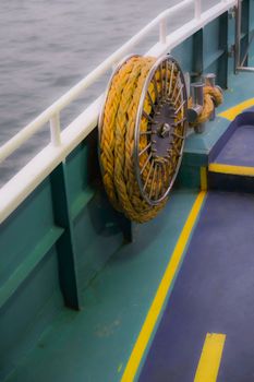 Close-up of rope coiled on ship deck with ocean in the background.