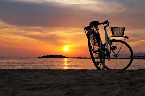在日落的棕色沙灘上的白色硬尾自行車