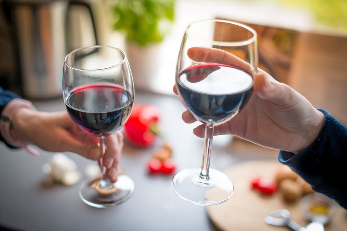 Close-up Photo of Two People Toasting With Red Wine