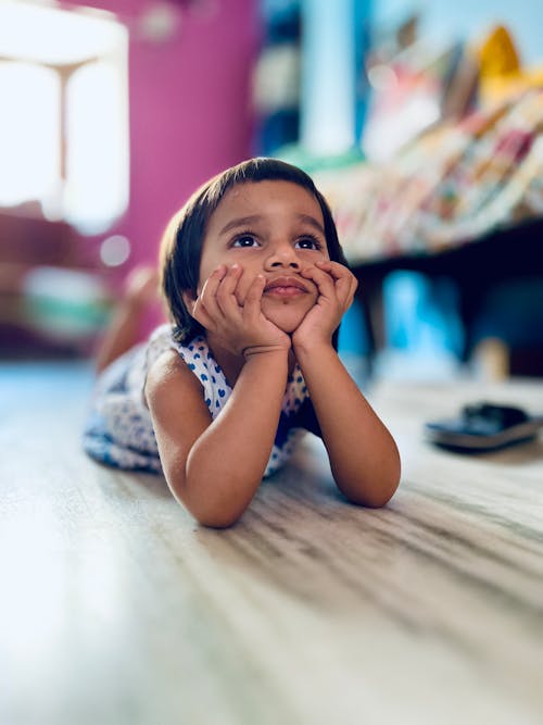 Free A little girl laying on the floor looking up at the camera Stock Photo