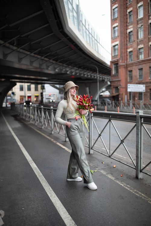Free Woman in urban setting holding bouquet, embodying modern street fashion with vibrant tulips. Stock Photo