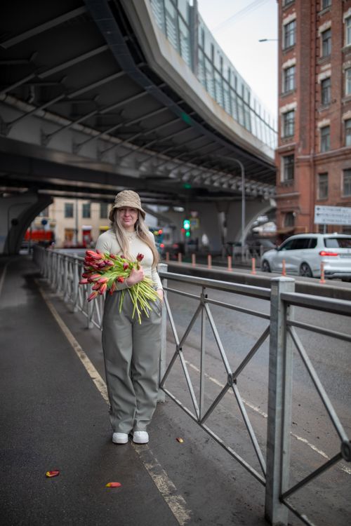 Free Woman in urban setting holding a bouquet of tulips, stylish attire. Stock Photo