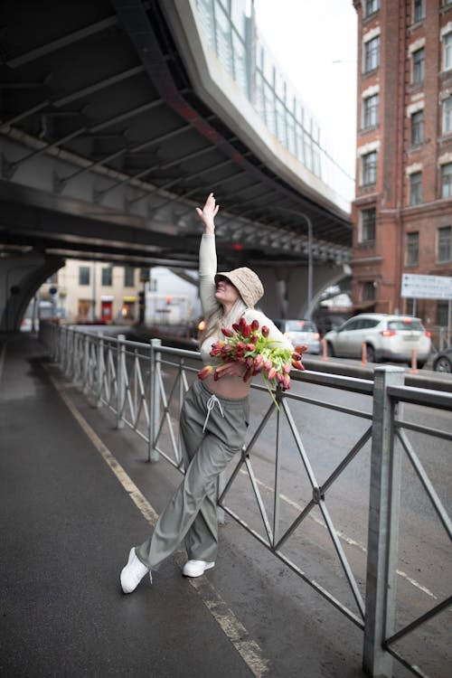 A woman is standing on a bridge holding a bouquet