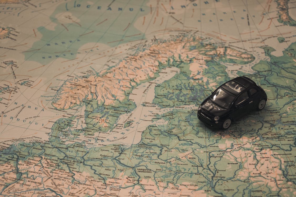 無料 世界地図の紙に黒いおもちゃの車 写真素材