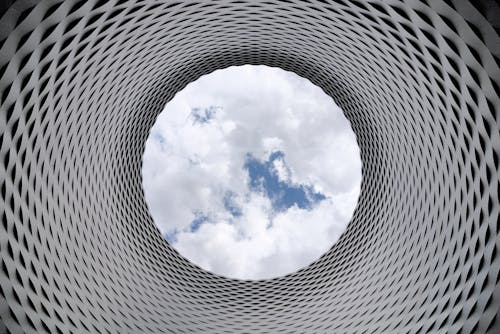無料 白い曇りと青い空を見下ろす灰色と黒のトンネルのローアングル写真 写真素材
