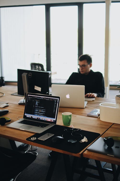 Free Man in Black Shirt Sits Behind Desk With Computers Stock Photo