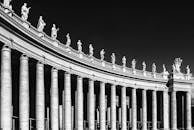 在晴朗天空的映衬下，梵蒂冈柱廊与雕像的黑白照片戏剧性地突出了经典建筑