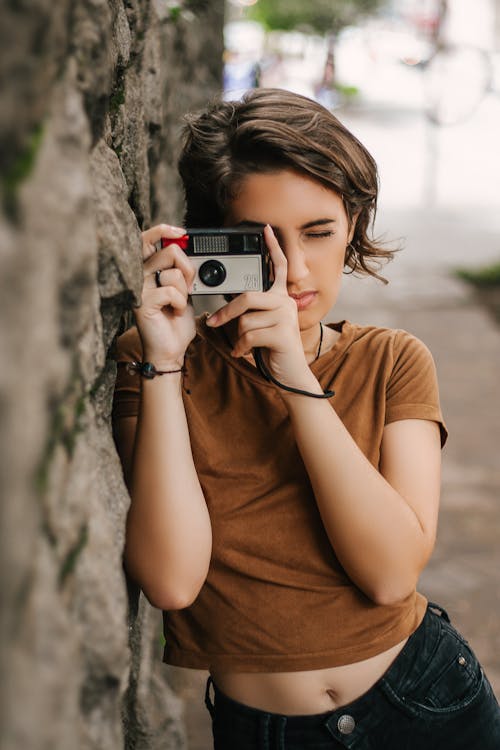 Woman Taking Photo While Leaning on Wall