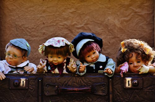 茶色の革のバッグの近くの4つの人形