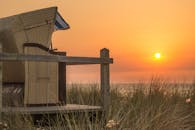 日落时分，宁静的海滩与柳条椅捕捉了自然之美和静谧