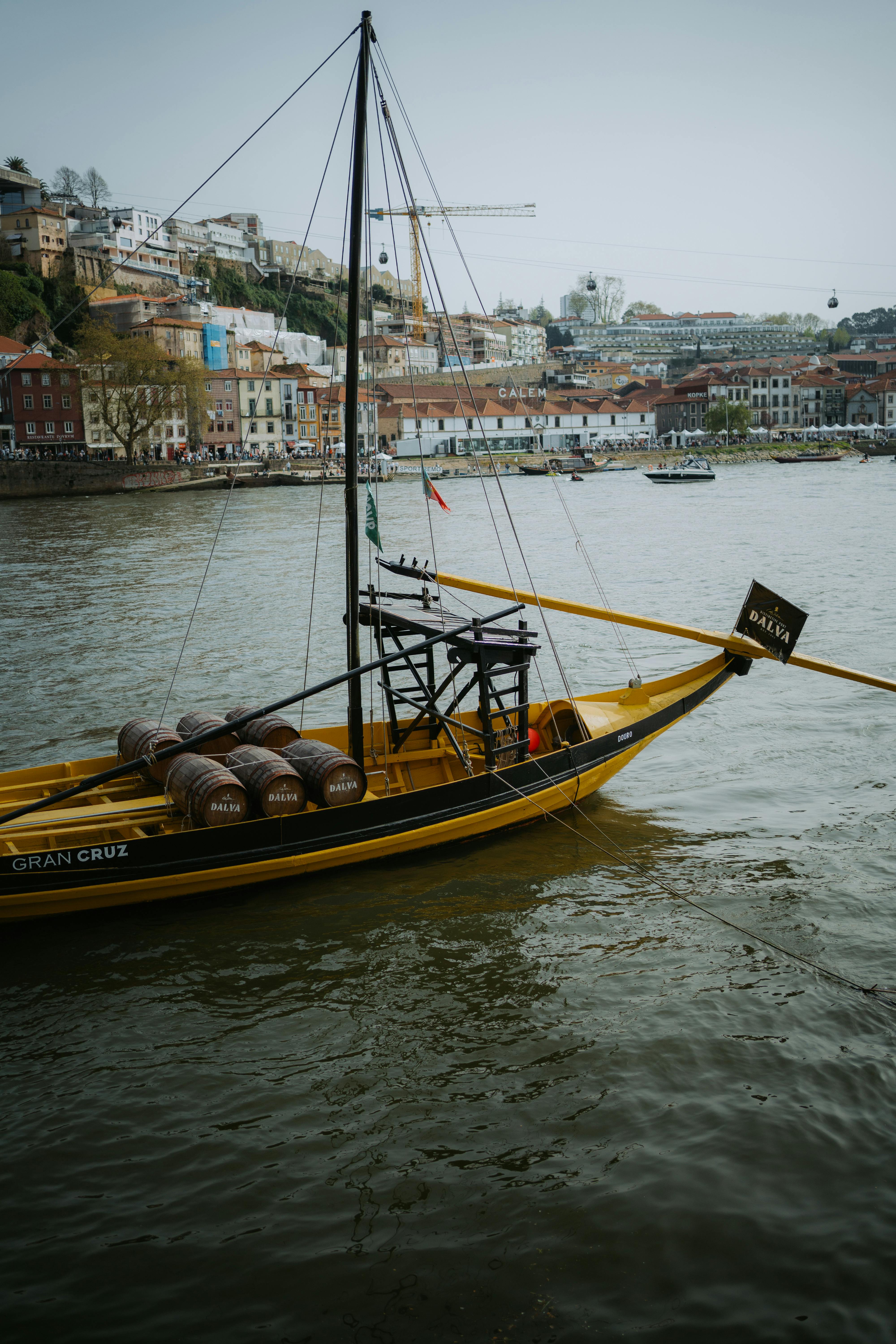 A classic Rabelo boat filled with barrels on the Douro River with Porto's cityscape in the background.