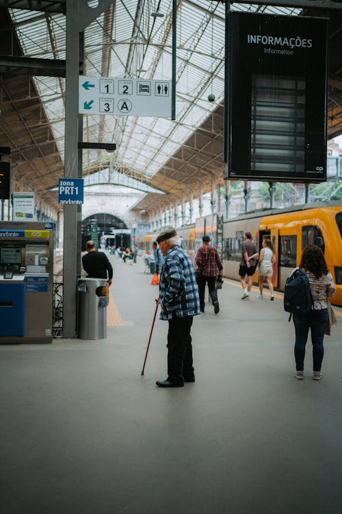 A man with a cane is walking through a train station