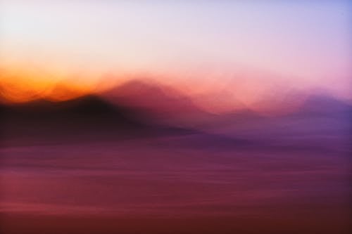 A blurry photograph of a sunset with mountains in the background