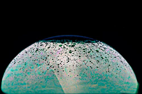 A glass ball with a green and blue speckled surface