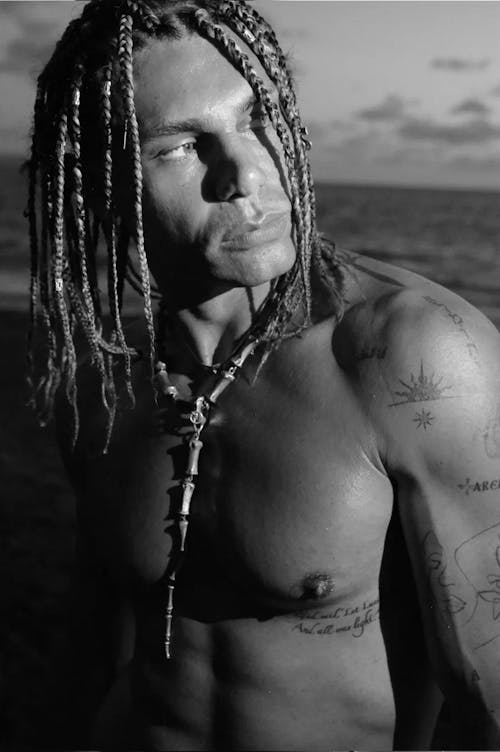A man with dreadlocks and tattoos on his chest