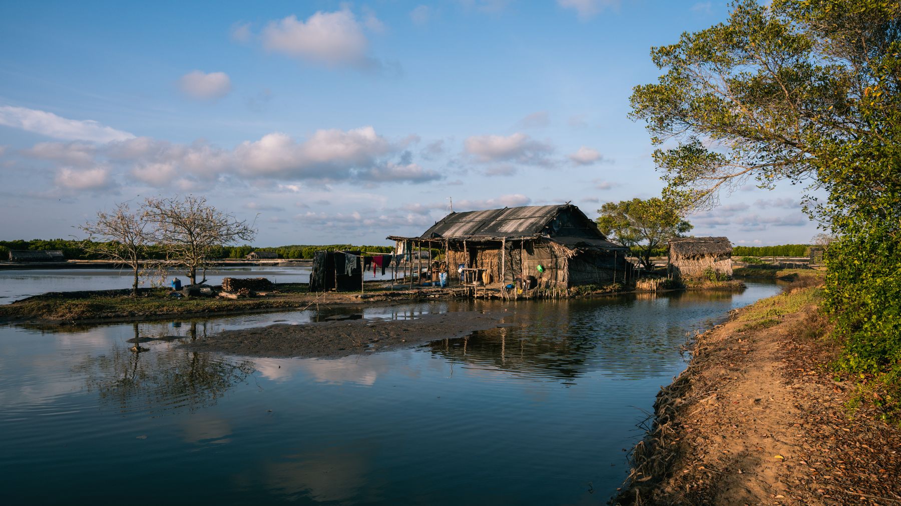 Rustic village houses on a lakeside in Ho Chi Minh City, Vietnam with sunny blue skies.