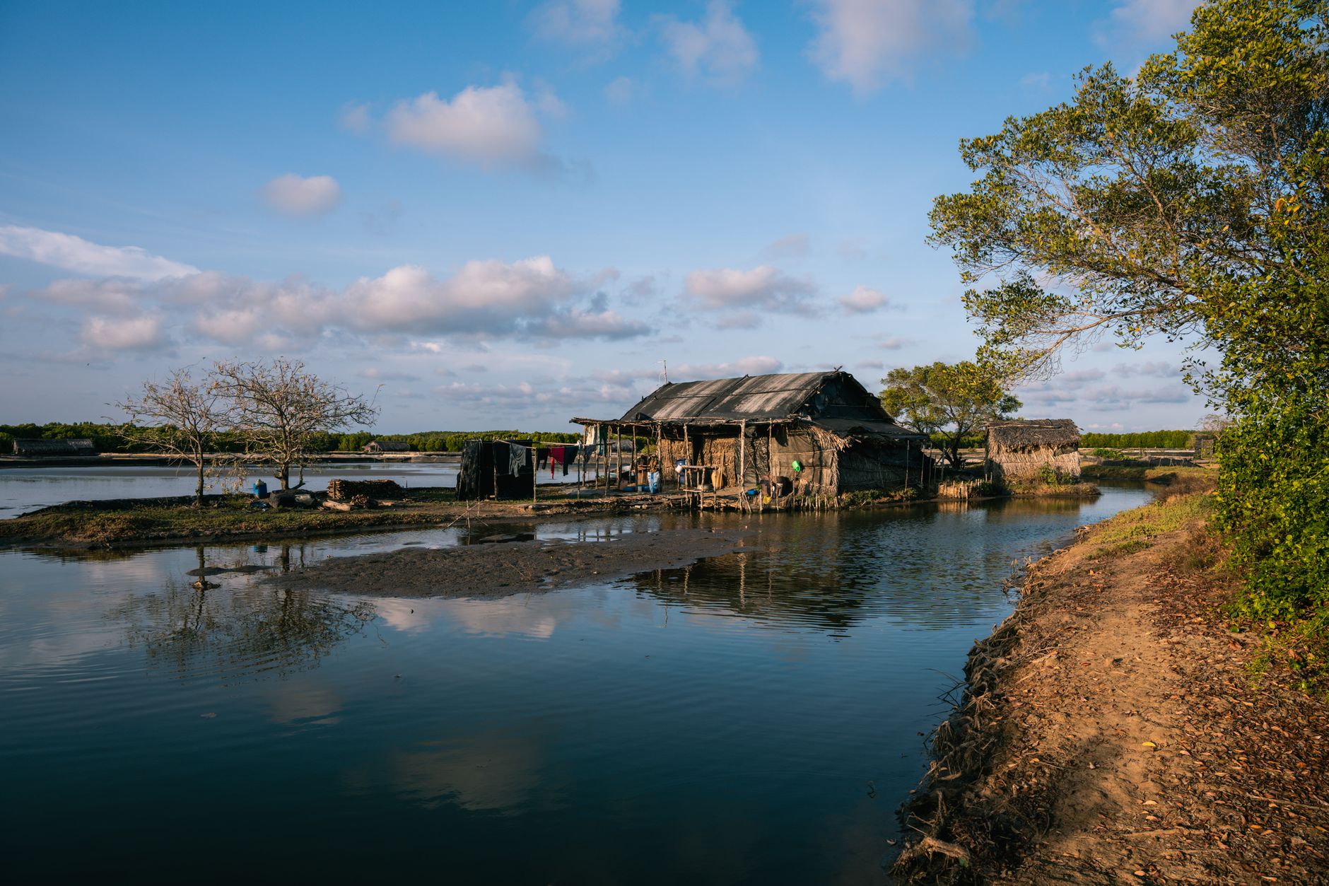 Rustic village houses on a lakeside in Ho Chi Minh City, Vietnam with sunny blue skies.