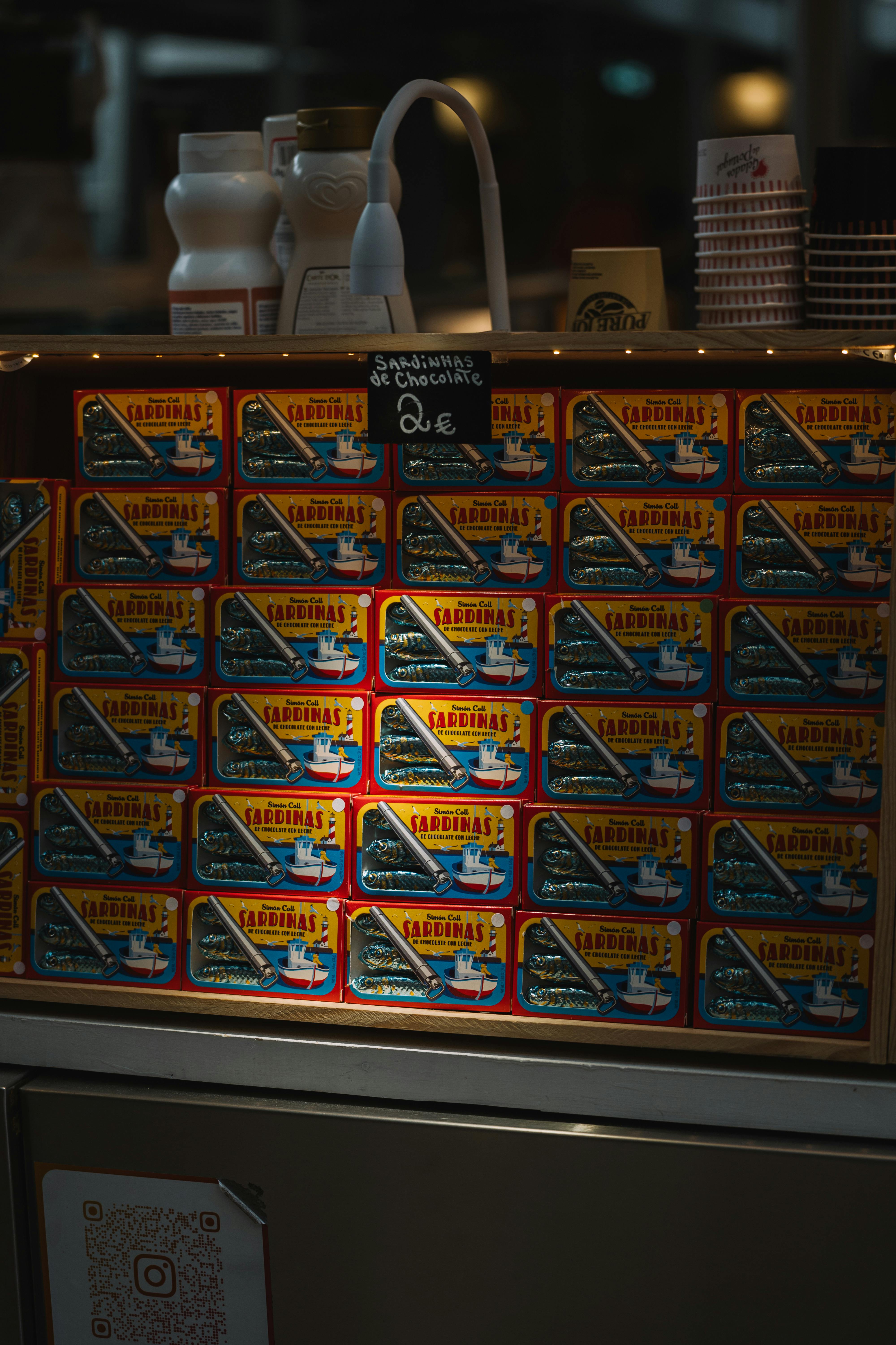 A stock of sardine cans for sale in a dimly lit market environment.