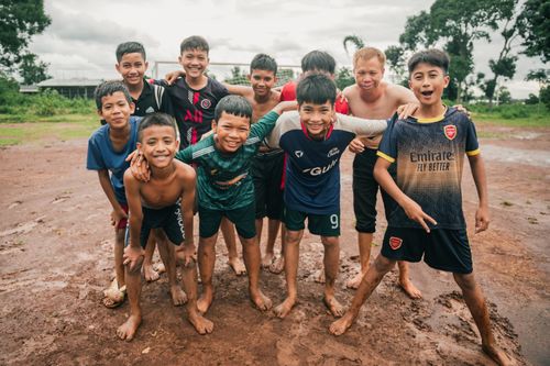 Free Smiling boys enjoying soccer in a muddy field in Buon Ma Thuot, Vietnam. Stock Photo