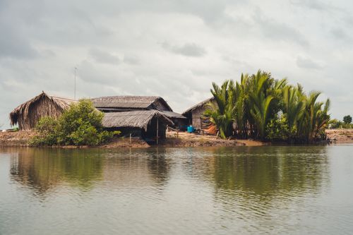 Free Traditional thatched huts on a small, lush island in Ho Chi Minh City, reflecting on a tranquil lake. Stock Photo