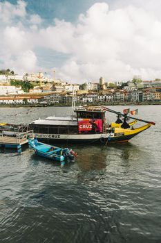 Colorful boats on Douro River with Porto cityscape in the background.